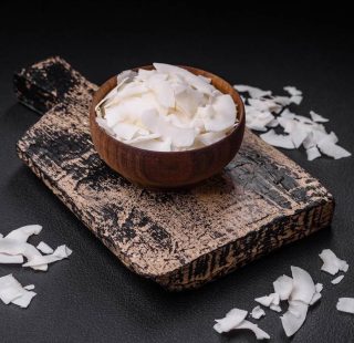 White dry coconut flakes in a wooden bowl prepared for making de